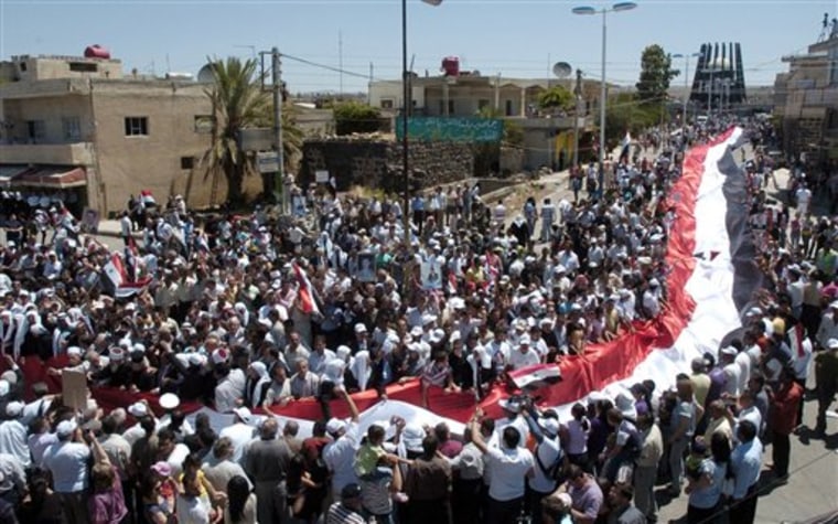In this photo released by the Syrian official news agency SANA, Syrian supporters of President Bashar Assad carry a giant national flag during a protest in al-Qarya village, in the southwestern Suwayda province, Syria, Friday, July 1, 2011. Tens of thousands of people took to the streets throughout Syria on Friday, including the capital and the major city of Aleppo, chanting for the downfall of President Bashar Assad's regime as government troops killed three more people in the northwest during a military siege, activists said. (AP Photo/SANA) EDITORIAL USE ONLY